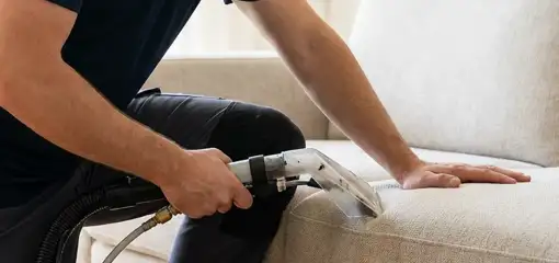 Professional upholstery cleaner deep-cleaning a fabric sofa with a handheld extraction tool, Santa Ana, CA.